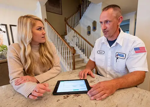 Dependaworthy Benjamin Franklin Plumbing technician, Daniel, consulting with a homeowner at the kitchen counter in Charlotte, NC